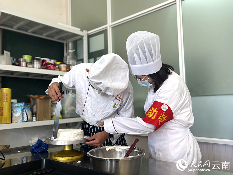 3西式面点制作实训课上,黄永灿(右)协助同学制作蛋糕。人民网-尹馨摄